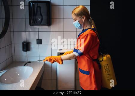 Cleaning lady spraying the sink with a disinfectant Stock Photo