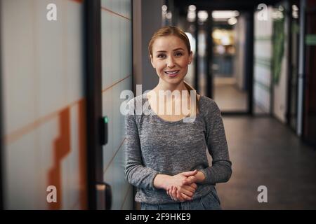 Smiling employee standing in the office corridor Stock Photo