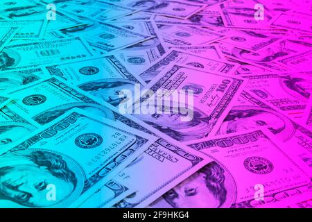 Stack of one hundred dollar bills. Stack of cash money in hundred dollar banknotes. Heap of hundred dollar bills background in blue and pink tones Stock Photo