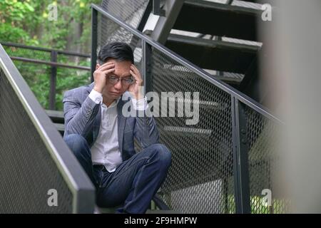 Stressed businessman sitting at stairway outdoor. Business crisis or work stress concept. Stock Photo