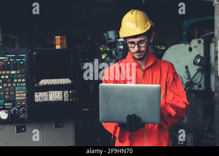 Skillful factory worker working with laptop computer to do procedure checklist . Factory production line operator occupation quality control concept . Stock Photo