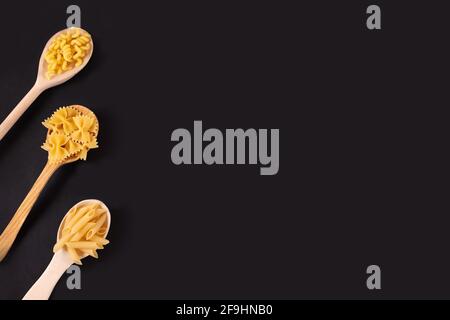 Different pasta types in wooden spoons on the table. Top view.  Stock Photo