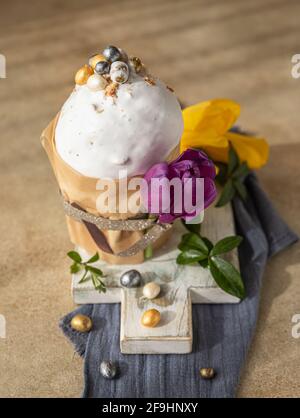 Easter composition with traditional Orthodox sweet bread. Kulich decorated with meringue icing, candy shaped eggs and tulip. Selective focus. Stock Photo