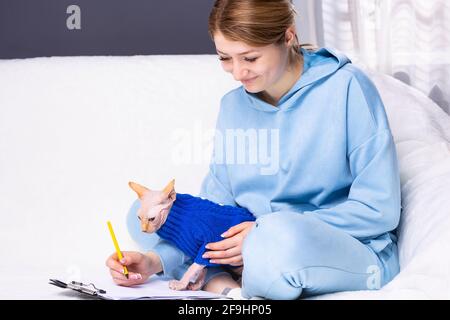 Businesswoman concentrated writes down notes on clipboard, works with favourite pet, pose in home office on sofa, work freelance. People, work Stock Photo