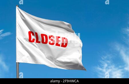 Closed - inscription by red letters on white flag against blue sky. Concept picture about closed road or border Stock Photo