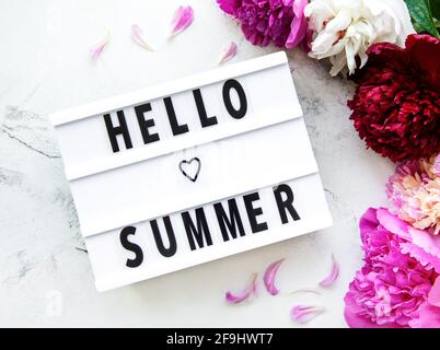 Light box with Hello Summer text and peonies flowers on a marble background Stock Photo