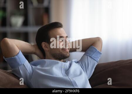 Smiling man relax at home dreaming looking in distance Stock Photo