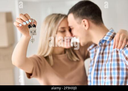 Happy young couple first time home owners holding keys in new home, closeup. Stock Photo
