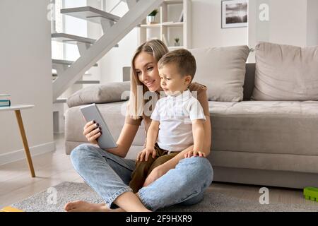 Happy family mom and cute child son holding digital tablet at home. Stock Photo