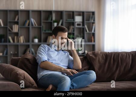 Young Caucasian man talk on cellphone at home Stock Photo