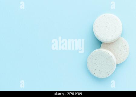 Heap of medicine pills on blue surface, isolated, top view. Stock Photo