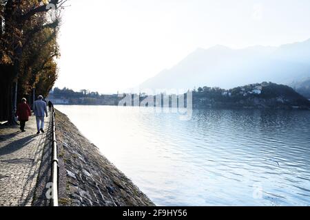 Senior elderly couple walking together outdoors along the italian mountain lake district Como. Lecco, Italy - November 11, 2020 Stock Photo
