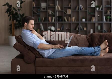 Pensive man look at laptop screen making decision Stock Photo