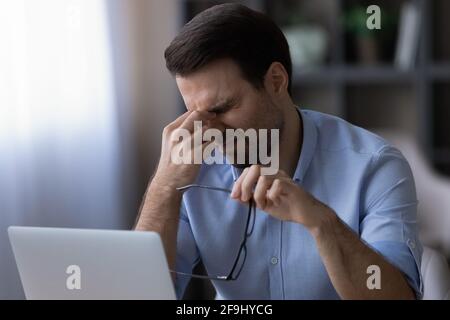 Exhausted man suffer from headache working on laptop Stock Photo