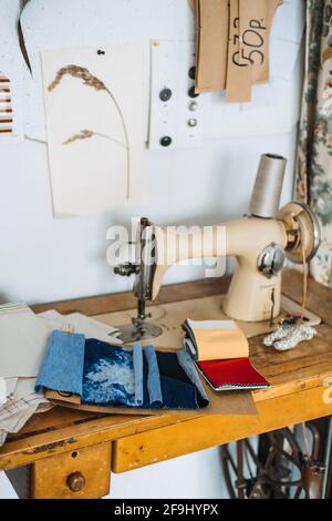 Supporting local, Tailoring small business. Seamstress, dressmaker, designer retro style workplace. Sewing machine with fabric samples, Threads and Stock Photo