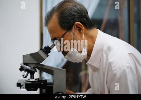 A Scientist Is Using A Microscope To Examine A Blood Sample. Test Tubes 