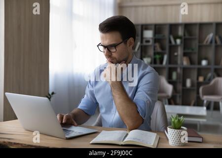 Pensive male work on laptop making notes Stock Photo