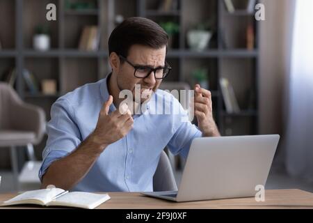 Unhappy man frustrated by computer operational problem Stock Photo