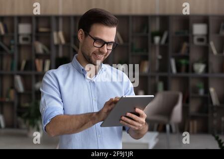 Smiling young man use modern tablet texting Stock Photo