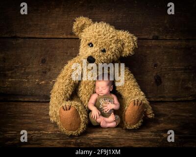 Baby holding gingerbread biscuit sleeping in the arms of mother teddy bear Stock Photo
