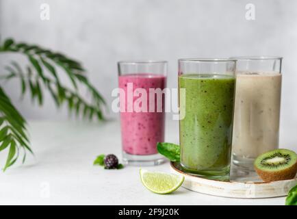 Colorful smoothie drinks with ingredients - kiwi, banana, blackberry. Natural Organic Food Style. gray background with green leaves. horizontal image Stock Photo