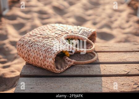 Traveling straw bag on wooden bridge near the sand beach. Resting at the resort. Stock Photo