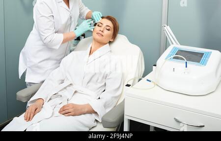 Mesotherapy procedure. Woman with closed eyes receives beauty injections for tightening and refreshing skin at medical clinic Stock Photo