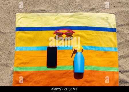 Towel, sunsreen, sunglasses and smart phone on the beach. Summer concept. Stock Photo