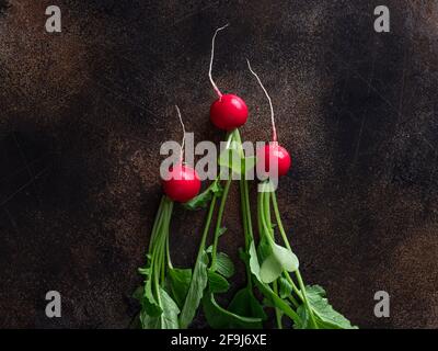 three radishes on dark brown table. Healthy nutrition