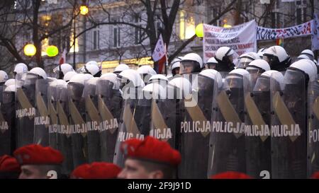 Warsaw, Poland 11.12.2018 Marsz Niepodleglosci - Nationalist supporters wearing helmets with banners. Poland's National Independence day. Military man in the foreground wearing red Beret.  Stock Photo