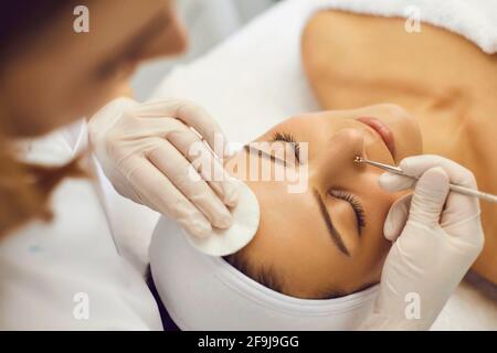 Professional cosmetician removing blackheads on client's nose with help of special tool Stock Photo