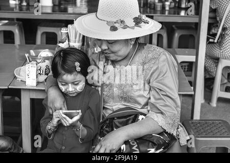 A Burmese Grandmother Looks On With Pride As Her Granddaughter Uses A Mobile Phone (Cellphone), Pindaya, Shan State, Myanmar. Stock Photo