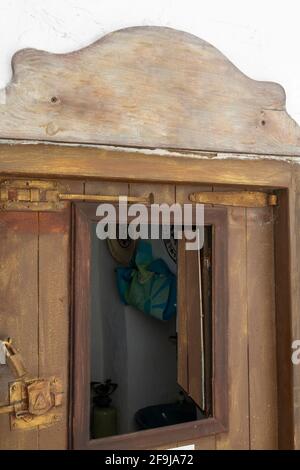 curious and old rustic wooden door with small open window in white house on the island of Mykonos Greece Stock Photo