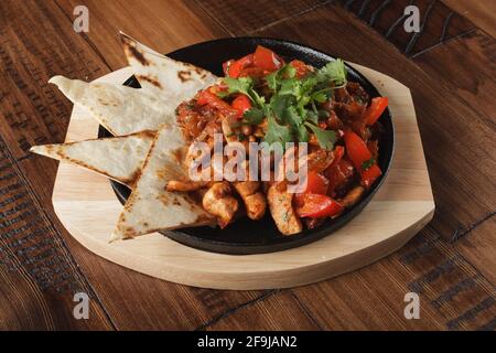 Fajitas with chicken and bell pepper in a pan. Wooden background. Stock Photo