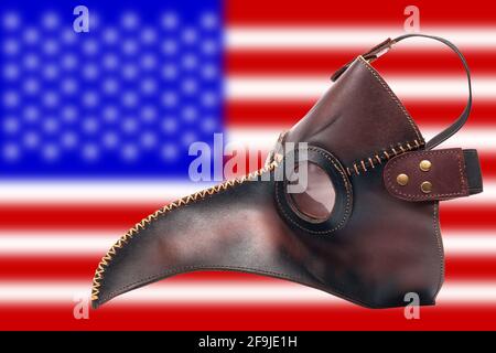 Protective medical mask of the plague doctor against the background of the USA flag. The concept of a mask regime for residents of the country and tourists in the United States during a pandemic. Stock Photo