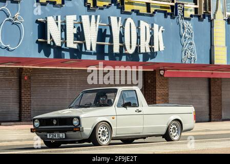 1989 Volkswagen Caddy pickup truck driving past closed New York amusement arcade in Southend on Sea, Essex, UK, on a sunny, bright Spring day. Stock Photo