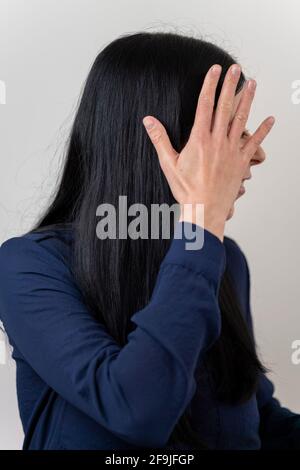 Shy young woman putting her hand in front of her face to protect her privacy Stock Photo