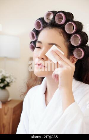 Beautiful young woman removing eye make-up with cotton pad with miccelar water Stock Photo