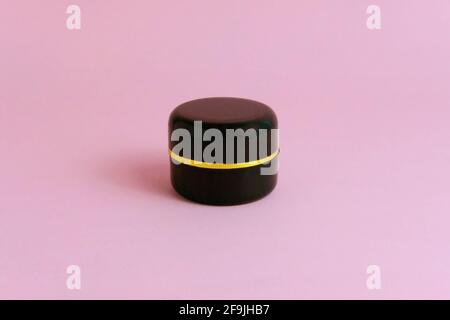 Front top view - black bottle makeup cream mock-up with pink background. Image photo Stock Photo