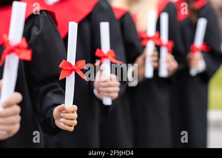 Unrecognizable multiracial group of graduates holding diplomas Stock Photo