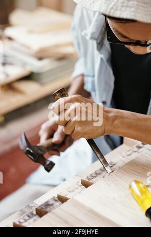 Close-up image of carpenter working with hard wood, he is using hammer and chisel Stock Photo