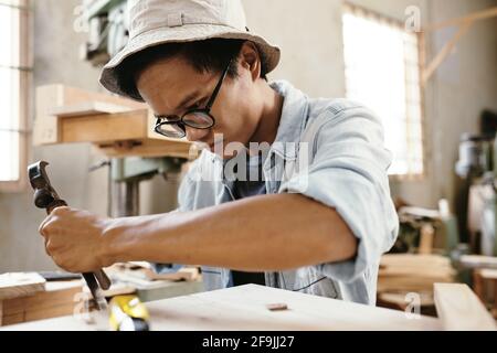 Carpenter concentrated on taking chunks out of surface of wood when making furniture piece Stock Photo