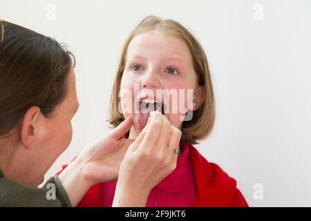 School age kid child primary school girl of 11 year old / years old having samples taken from her throat for use in a lateral flow test LFT from the Chinese company Innova. England UK. (123) Stock Photo