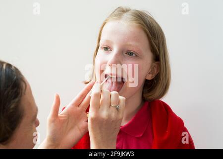 School age kid child primary school girl of 11 years / year old having samples taken from her throat for use in a lateral flow test LFT from the Chinese company Innova. England UK. (123) Stock Photo