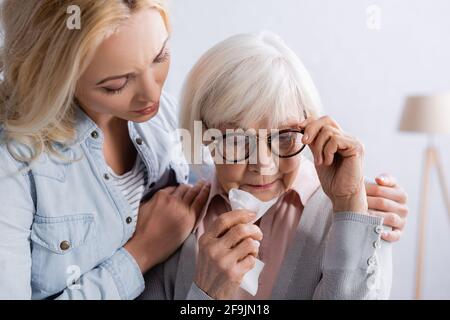 Upset senior woman with napkin standing near daughter Stock Photo