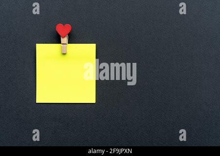 Yellow sticker with a clothespin on a black background. Stock Photo