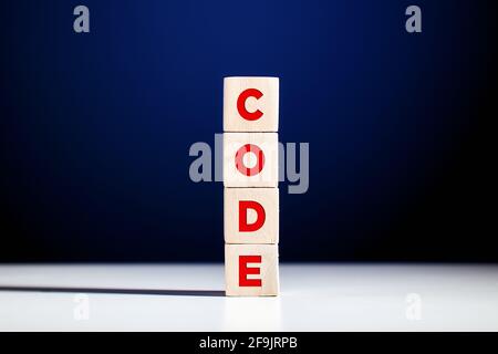 The word code written on tiered wooden cubes against blue background. Stock Photo