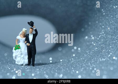 Bride and groom miniature people walk out on a tunnel full of silver and white bokeh light after wedding. Image photo Stock Photo