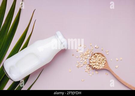 Bottle with daity free oat milk and dry oats in the spoon. Stock Photo