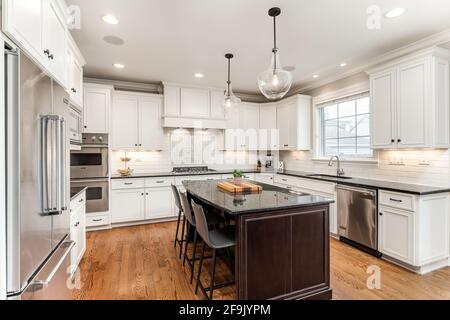 A modern farmhouse kitchen with white cabinets, a wood island with chairs,  Viking stainless steel appliances, and a dark granite countertop Stock  Photo - Alamy